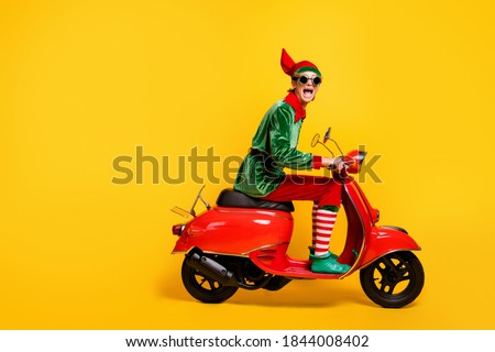 Profile side view of his he nice attractive crazy cheerful cheery funny teenage guy elf riding moped having fun festal day isolated over bright vivid shine vibrant yellow color background