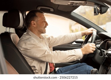 Profile side view of middle aged man driving car and paying attention to the road with both hands on steering wheel. Ideal driving condition