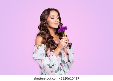 Profile side view photo of lovely, brunette young woman hold small bouquet of summer flowers in hand and breathe in their smell isolated on shine teal background stand half a turn