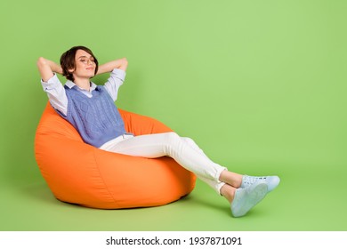 Profile Side View Portrait Of Attractive Dreamy Girl Sitting In Bag Chair Resting Isolated Over Green Color Background