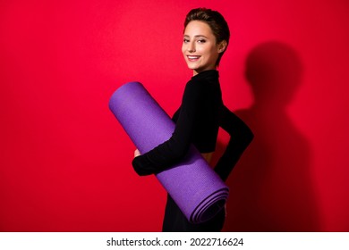 Profile Side View Portrait Of Attractive Cheerful Girl Trainer Holding Yoga Mat Crossfit Studio Isolated Over Bright Red Color Background