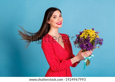 Profile side view portrait of attractive cheerful dreamy girl holding in hands blossom air blowing hair isolated over bright blue color background