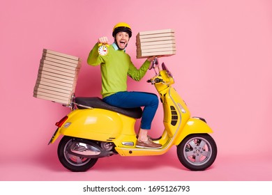 Profile side view portrait of his he nice attractive cheerful cheery guy driving moped bringing pile stack pizza order time early morning holding watch isolated over pink pastel color background
