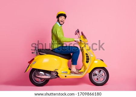 Profile side view portrait of his he nice attractive crazy overjoyed glad cheerful cheery guy driving moped having fun traveling isolated over pink pastel color background