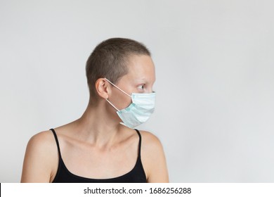 Profile Side View Of Short Haired Young Adult Woman Wearing Protective Facial Mask On Face Against Wall Indoors. Coronavirus Outbreak Prevention. Vulnerable Category Person. Virus Pandemic Awareness.