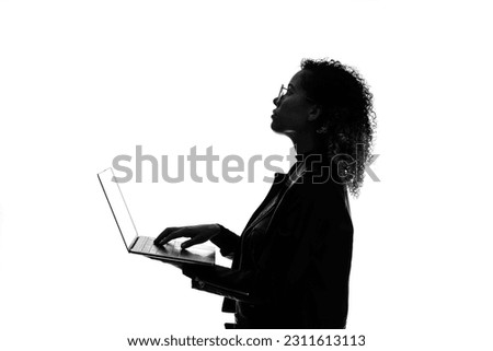 Profile silhouette of black woman using laptop PC in studio shot.
