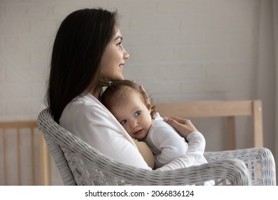 Profile Of Smiling Mother Hugging Little Daughter, Sitting In Cozy Chair At Home, Happy Loving Young Mom Embracing Adorable Toddler Child Girl, Family Enjoying Tender Moment, Motherhood Concept