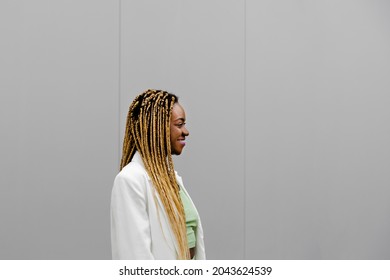 Profile Of Smiling Young African American Woman With Long Blond Braids. Copy Space.