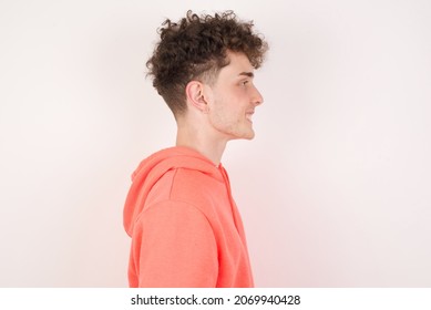 Profile of smiling young caucasian man with curly hair wearing sweatshirt ​white background with healthy skin, has contemplative expression, ready to have outdoor walk. - Powered by Shutterstock