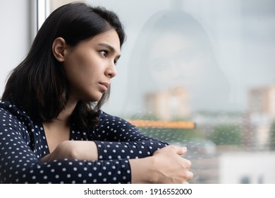 Profile of stressed young asian lady sitting on sill by window think hesitate unable to make choice in hard situation. Suffering teen vietnamese female with depressed look has life crisis. Copy space