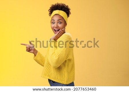 Profile studio shot amused impressed speechless cute stylish shopping girl drop jaw amazed widen eyes turning camera surprised cover open mouth palm pointing left index finger show cool promo