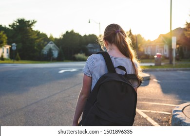 Profile Of A Teen Girl Depressed/sad At Sunset In A Parking Lot While Wearing A Backpack.