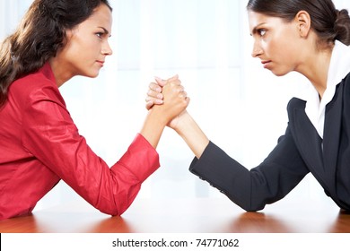 Profile of two women in struggle while their arms being wrestled