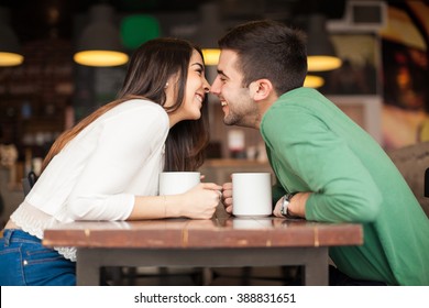 Profile View Of A Cute Young Couple Reaching Across The Table And About To Kiss