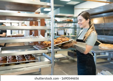 Profile View Of A Female Baker Carrying Some Freshly Baked Bread Out Of The Oven And Smiling