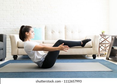 Profile View Of Fit Young Lady Stretching And Doing Boat Yoga Pose In Living Room