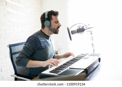 Profile View Of Good Looking Latin Man With Headphones Playing Piano And Singing Into A Mic, Singing Over Online Radio Show.