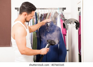 Profile View Of A Good Looking Young Man Using A Steamer On A Shirt Before Getting Dressed