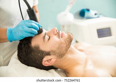 Profile View Of A Good Looking Young Man Getting A RF Facial Treatment In A Health Spa