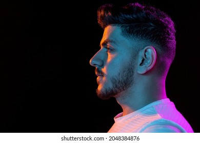 Profile View. Latino Young Man's Portrait On Black Studio Background In Neon Light. Handsome Male Model. Concept Of Human Emotions, Facial Expression, Youth, Sales. Copy Space For Ad.