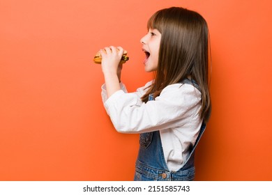 Profile View Of A Little Girl Opening Her Mouth Wide Open To Give A Hamburger A Big Bite In A Studio