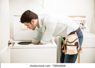 Profile View Of A Male Technician Inspecting And Fixing A Washer And Dryer In A Laundry Room