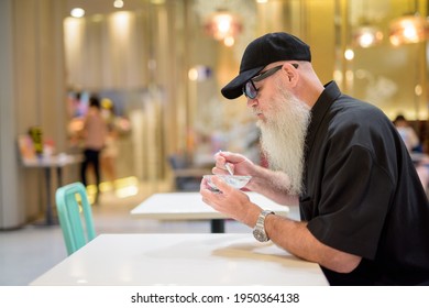 Profile View Of Man Sitting In Shopping Mall And Eating Ice Cream