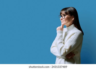 Profile view of middle aged happy woman, blue background, copy space