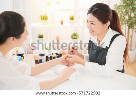Profile view of a pretty young mixed asian women enjoy manicure and talking with her manicurist at real salon spa background. beauty and fashion concept.