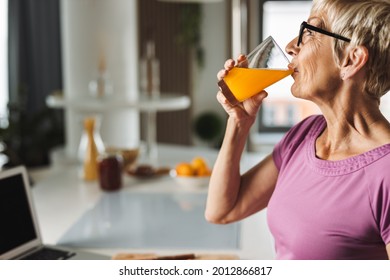 Profile view of a senior woman drinking fresh juice in the kitchen - Powered by Shutterstock