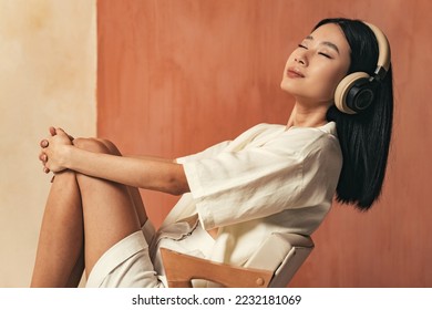 Profile view studio shot of relaxed asian woman with wireless headphones, listening to meditation music with closed eyes, smiling with pleasure after work day - Shutterstock ID 2232181069