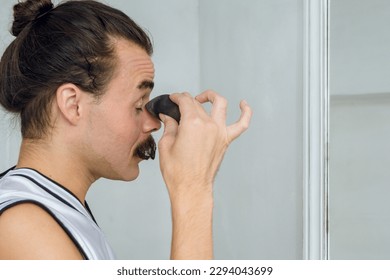 Profile view of a young Argentinian Latina person of non-binary gender in her room putting makeup on her eyelids with a sponge, applying foundation to start makeup., copy space, - Powered by Shutterstock