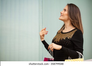 Profile View Of A Young Brunette Carrying Many Shopping Bags And Looking Up Towards Copy Space