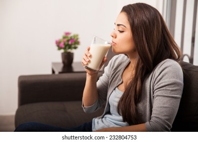 Profile View Of A Young Brunette Taking A Sip From A Glass Of Milk In The Living Room