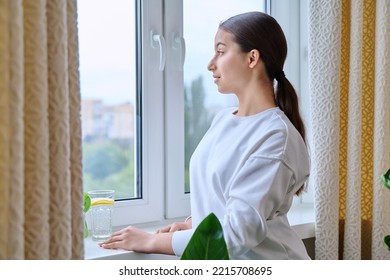 Profile View Of Young Calm Female Looking Out The Window In Distance