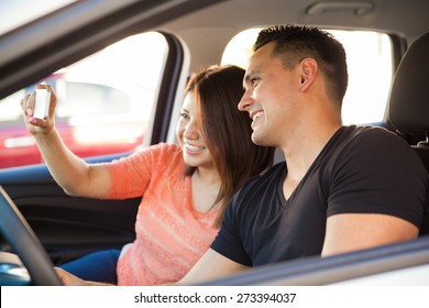 Profile view of a young couple taking a selfie with a smartphone while driving a car - Shutterstock ID 273394037
