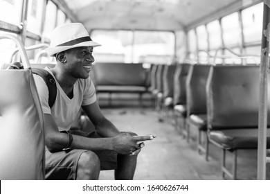 Profile view of young happy African tourist man using mobile phone while riding the bus - Powered by Shutterstock - Get 15% off with code: PIKWIZARD15