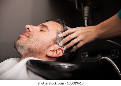 Profile view of a young man getting his hair washed and his head massaged in a hair salon - Powered by Shutterstock