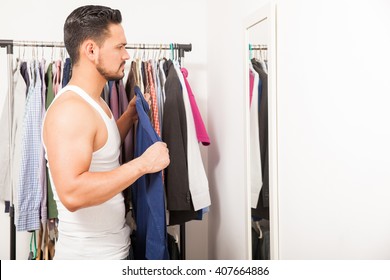 Profile View Of A Young Man Trying A Shirt On In Front Of A Mirror While Getting Dressed In His Bedroom