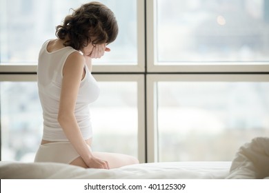 Profile View Of Young Pregnant Woman Sitting On The Bed Covering Her Mouth Feeling Nauseous In 1st Trimester Of Pregnancy. Copy Space. Morning Sickness