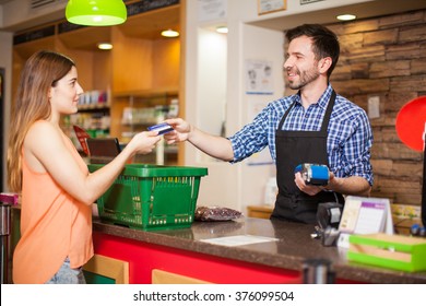 Profile view of a young woman paying with a credit card to a store clerk in a supermarket