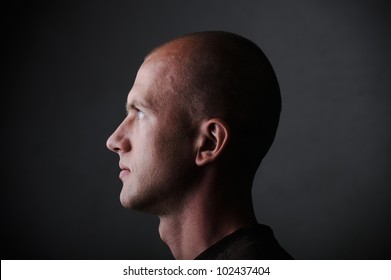 Profile of white bald man in his twenties in dark