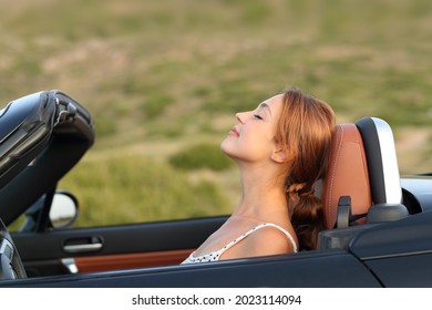 Profile of a woman breathing fresh air in a convertible car