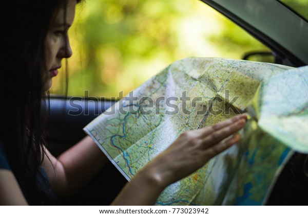 Profile of a woman holding a map and pointing on it\
while searching a city\
.