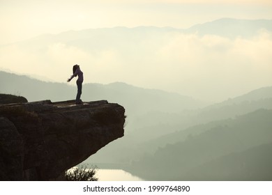 Profile of a woman silhouette screaming in the top of a cliff in the mountain with a beautiful landscape in the background