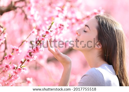 Profile of a woman smelling flowers in a pink field a sunny day