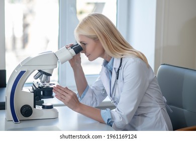 Profile Of Woman In Uniform Looking Through Microscope