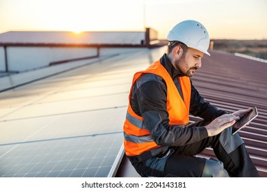 Profile of worker using tablet and testing solar panels on the roof. - Shutterstock ID 2204143181