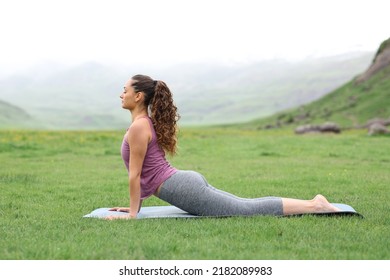 Profile Of A Yogi Doing Yoga Exercise In A Green Field In The Mountain