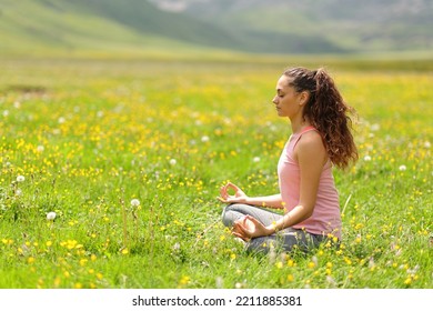 Profile Of A Yogi Doing Yoga Exercise In Mountain Green Field